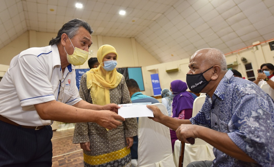  Pengurus Besar (Hal Ehwal Korporat) TNB, Datuk Omar Sidek (kiri) menyampaikan sumbangan kepada salah seorang penerima sumbangan, Sabarudin Manaf (kanan) di majlis penyampaian di Dewan Siantan Majlis Daerah Kuala Selangor (MDKS).